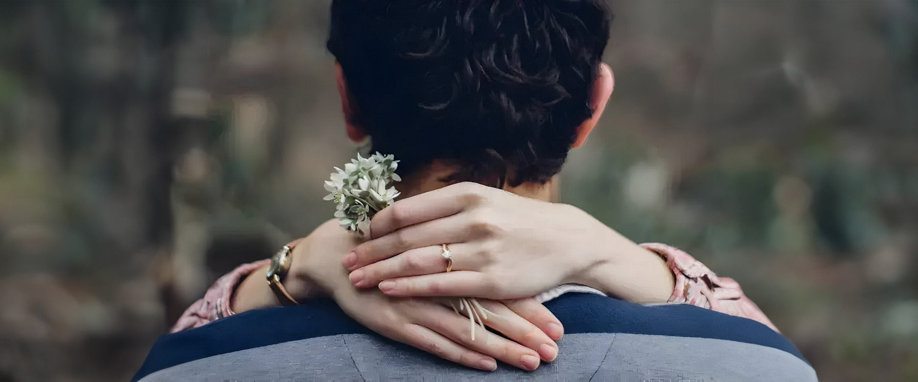 A female embracing a male with her hands round his neck