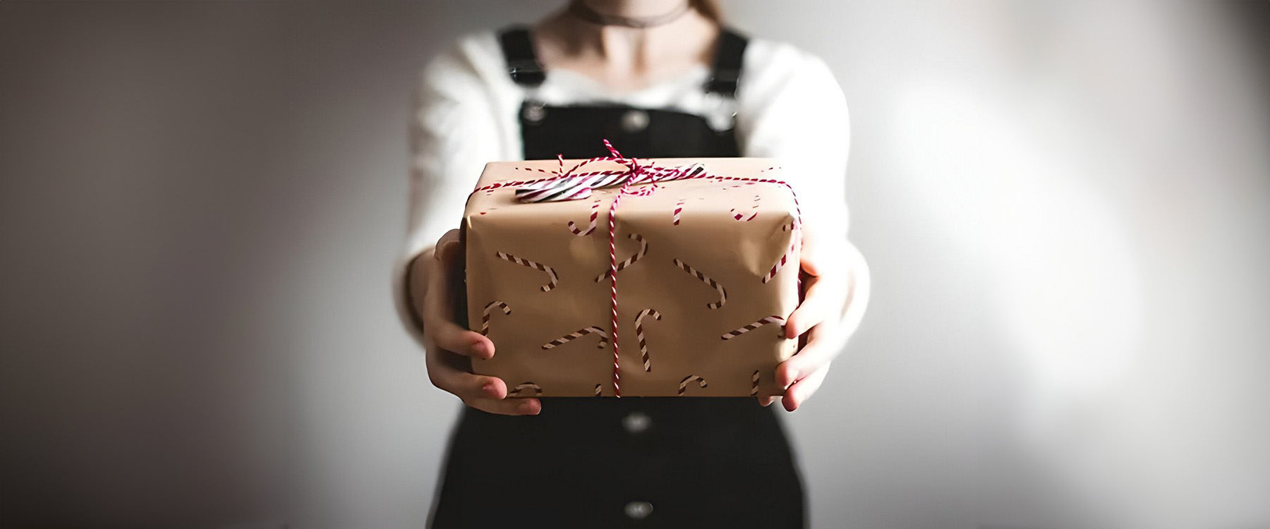 a gift wrapped in brown wrapping paper with candy canes on, and red ribbon.