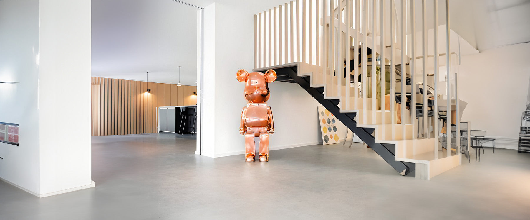 a rose gold giant bear sculpture at the bottom of the stairs in a house 