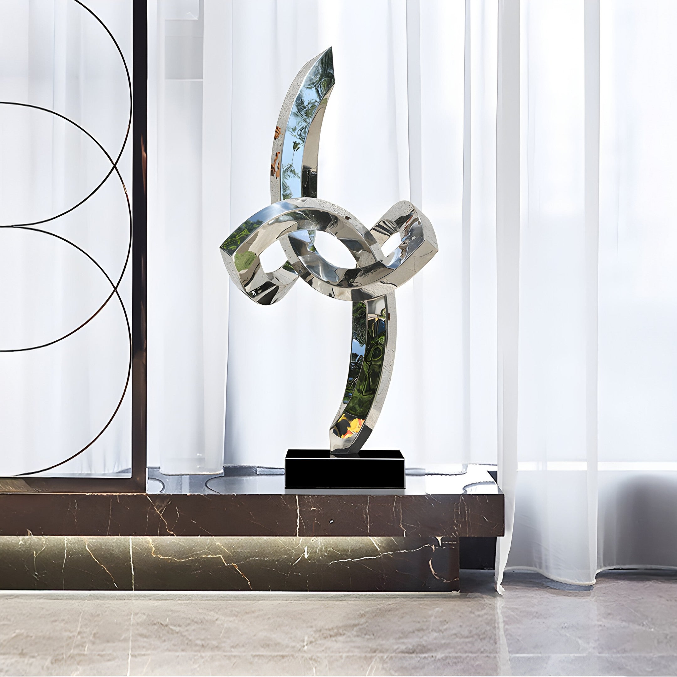 Infinity Twist stainless steel sculpture displayed in a minimalist interior, showcasing the elegant reflective curves against a bright room backdrop