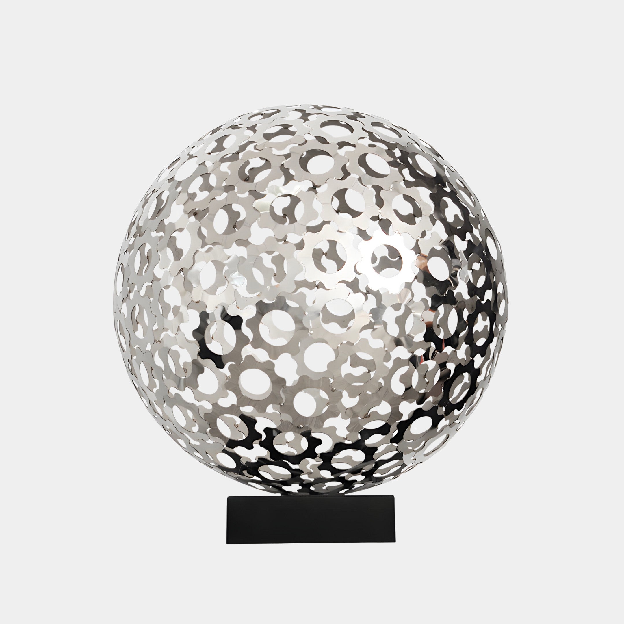 A silver stainless steel sculpture with intricate circular cutouts, placed on a black base, reflecting a sleek and modern design, perfect for indoor and outdoor décor.